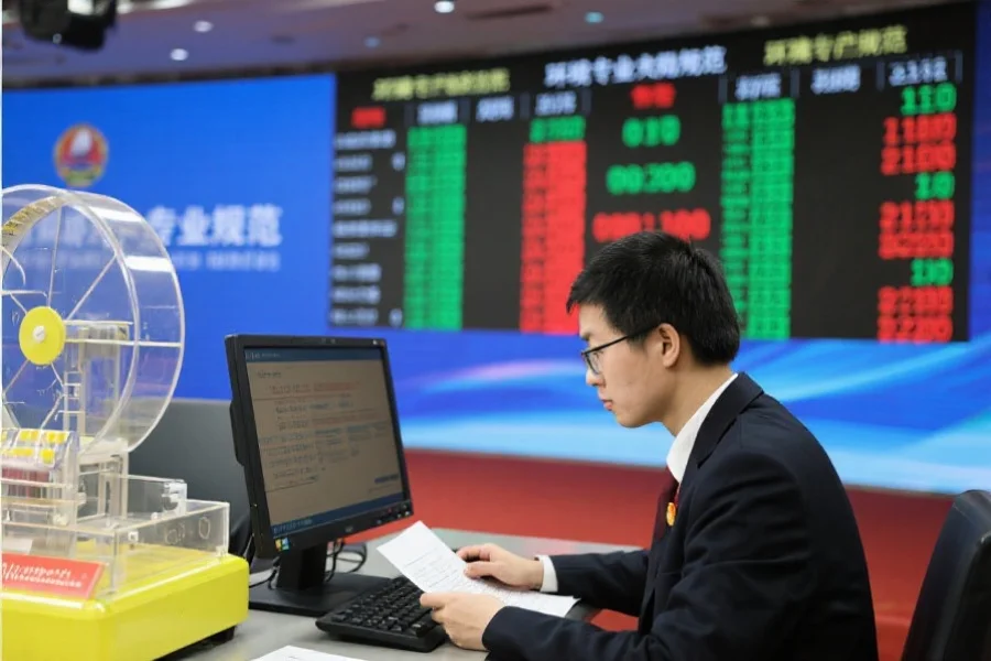 一位工作人员在电脑前认真核对摇号结果，背景为显示开奖结果的电子屏幕，环境专业规范